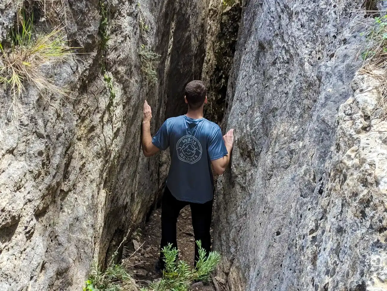 Persona dentro de una gruta entre dos paredes rocosas