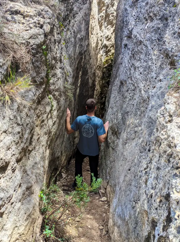 Persona dentro de una gruta entre dos paredes rocosas